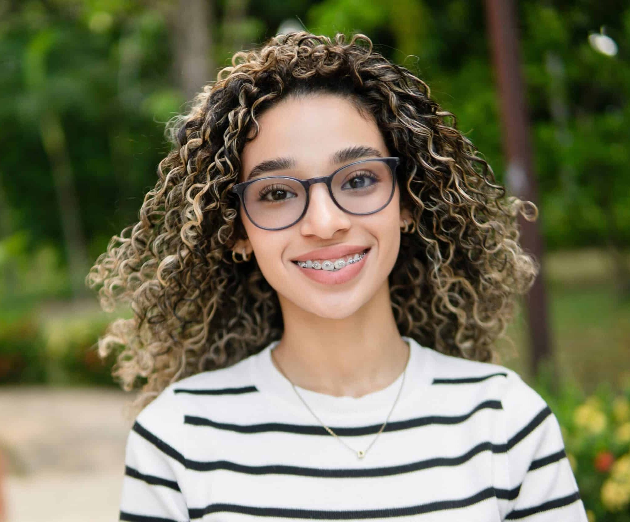 Young,Hispanic,University,Student,Smiling,,Wearing,Braces,And,Glasses,,Standing
