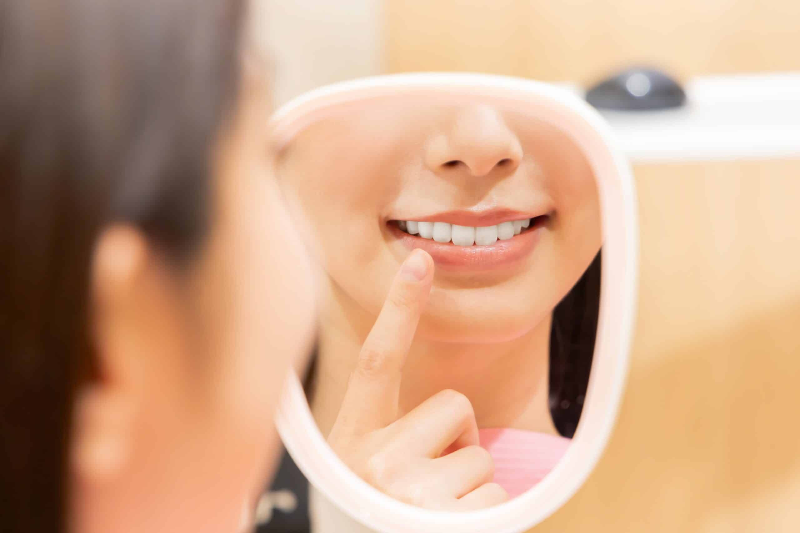 Woman,Checking,Her,Teeth,With,A,Hand,Mirror