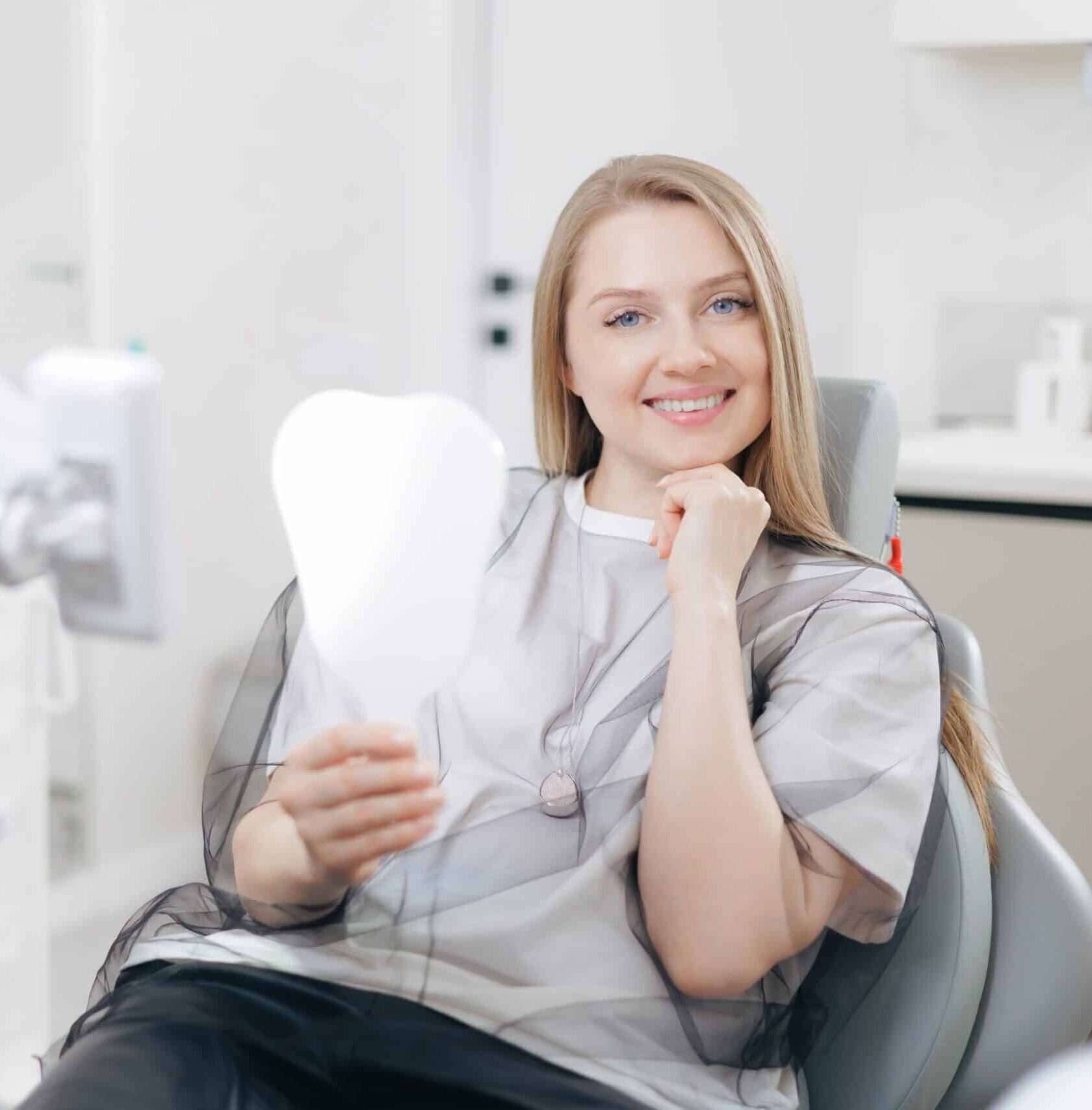 Caucasian,Young,Female,In,Dental,Clinic,Smiling,With,Tooth-shaped,Mirror.
